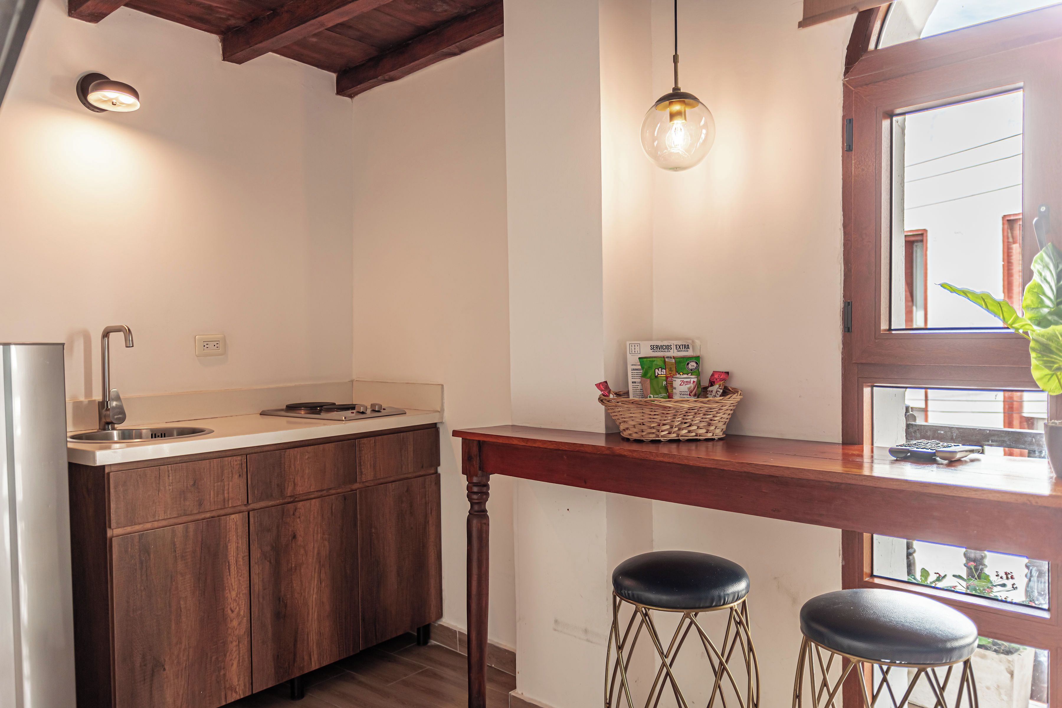 A kitchen with wooden cabinets, a stainless steel sink, a hanging light fixture, and a window with a view.