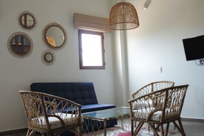 A living room with a blue sofa, wicker chairs, a glass coffee table, and a woven light fixture. - Soy Local Centro Historico (Cartagena)