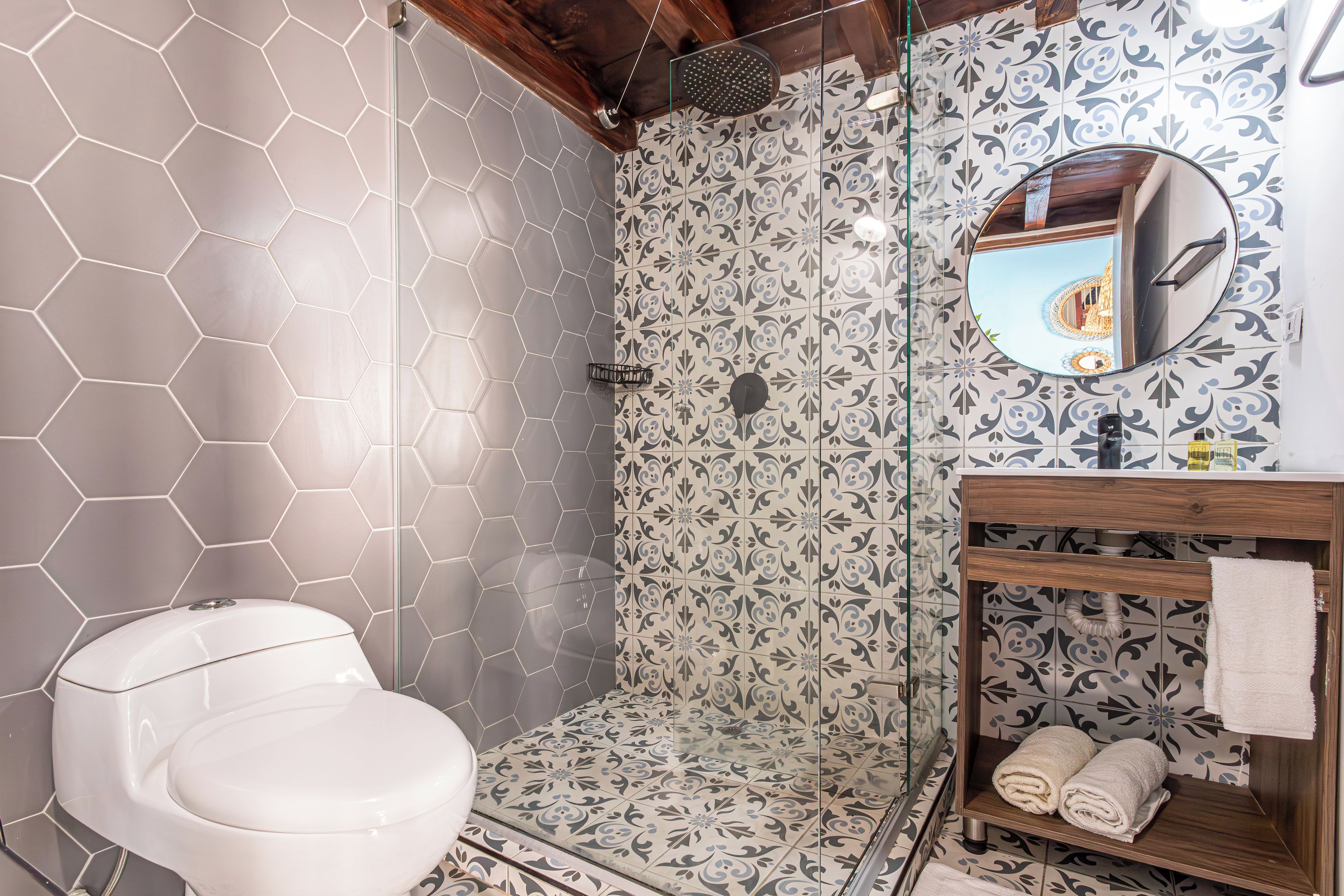 A bathroom with a white toilet, a shower with glass doors, and a wooden vanity with a mirror.