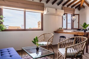 A room with a large window, wicker furniture, a glass table, and a view of a building outside. - Soy Local Centro Historico (Cartagena)