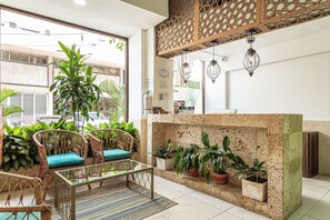 A reception area with wicker furniture, a glass-top table, potted plants, a fireplace, and hanging pendant lights. - Soy Local Centro Historico (Cartagena)
