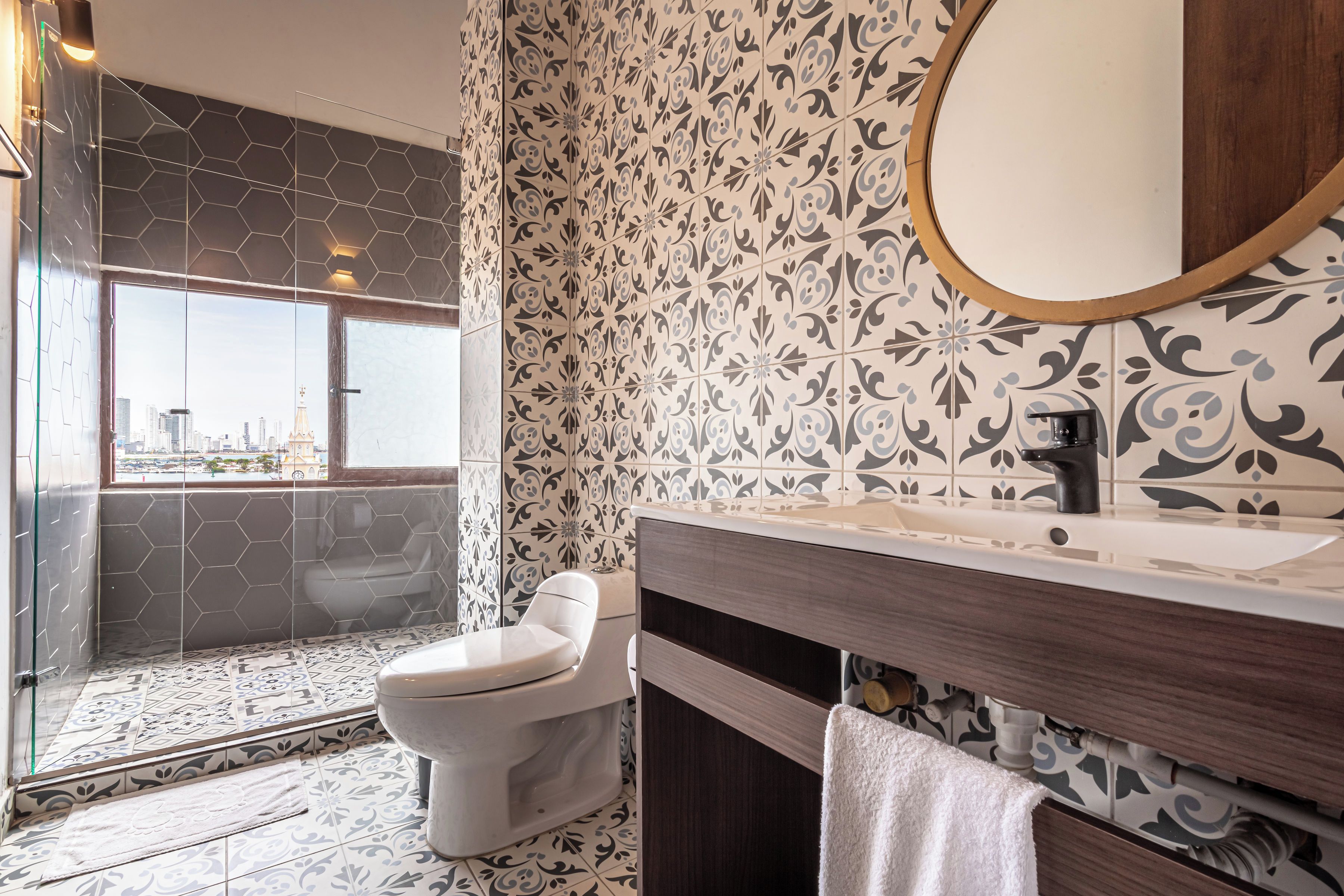 A bathroom with a toilet, a sink, and a shower area with a view of the city.