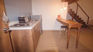 A kitchen with wooden cabinets, a countertop, a toaster, and a table with stools.