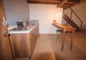 A kitchen with wooden cabinets, a countertop, a toaster, and a table with stools. - Soy Local Centro Historico (Cartagena)