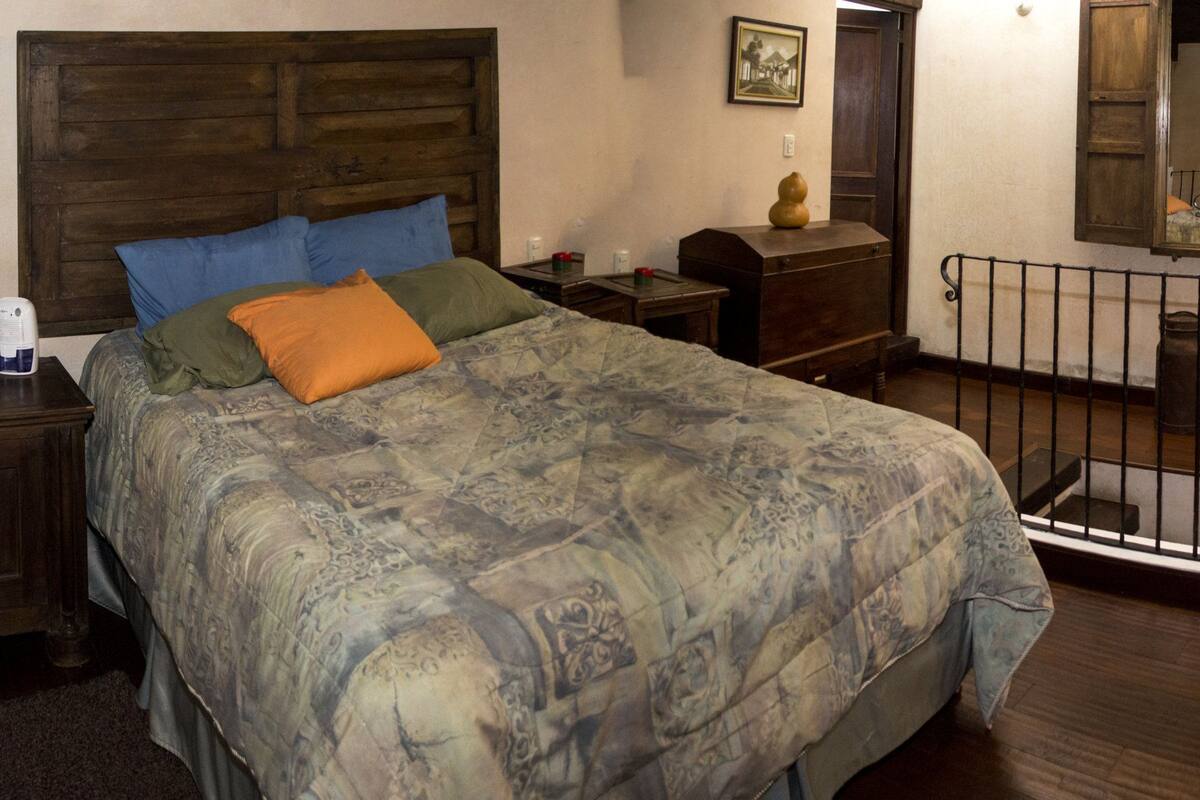 Ein Schlafzimmer mit einem großen Bett, einem Holzkopfstück und rustikaler Einrichtung, darunter ein Holzrad und eine Metalllaterne.
