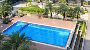 A rooftop pool with palm trees and a seating area.