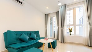 A modern living room with a teal sofa, a round coffee table, and a window with curtains.