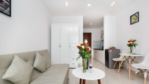 A modern living room with a sofa, a dining table with chairs, and a kitchen area in the background.