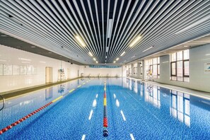 An indoor swimming pool with a blue tiled floor, white walls, and a ceiling with parallel lines. - Holiday Inn Hangzhou Airport Zone by IHG (Hangzhou)