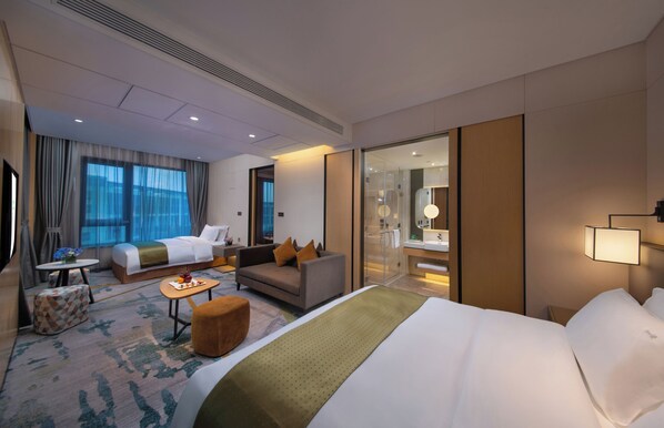 A hotel room with a large bed, a sofa, a small table, and a glass shower area. - Holiday Inn Hangzhou Airport Zone by IHG (Hangzhou)