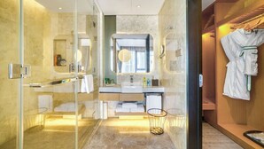 A modern bathroom with a glass shower enclosure, a vanity with a mirror, and a robe hanging on a rack. - Holiday Inn Hangzhou Airport Zone by IHG (Hangzhou)