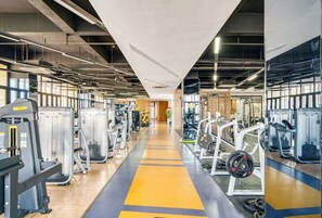 A gym with various exercise machines, a central walking path, and large windows allowing natural light. - Holiday Inn Hangzhou Airport Zone by IHG (Hangzhou)