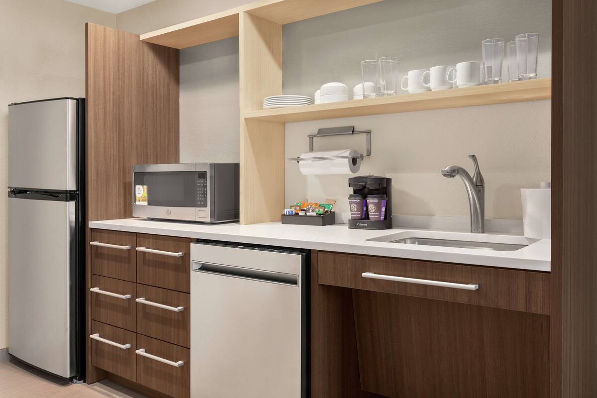 A modern kitchen with a built-in dishwasher, a microwave, and a coffee maker.