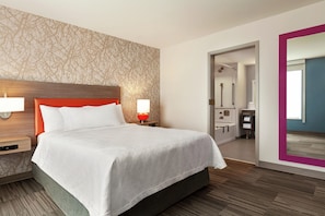 A hotel room with a bed, nightstands, a mirror, and a bathroom visible through an open door. - Home2 Suites by Hilton Silver Spring (Silver Spring)