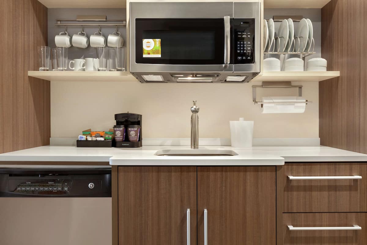 A modern kitchen with a built-in microwave, a coffee maker, and a dish rack.