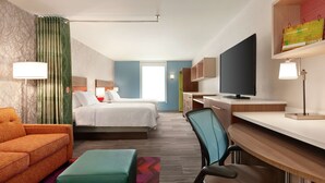 A hotel room with two beds, a desk, a TV, and a sofa. - Home2 Suites by Hilton Silver Spring (Silver Spring)