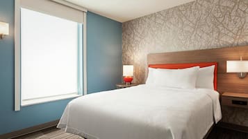 Ein Hotelzimmer mit einem großen Bett, zwei Nachttischlampen, einem Fenster und einer Wand mit Muster.