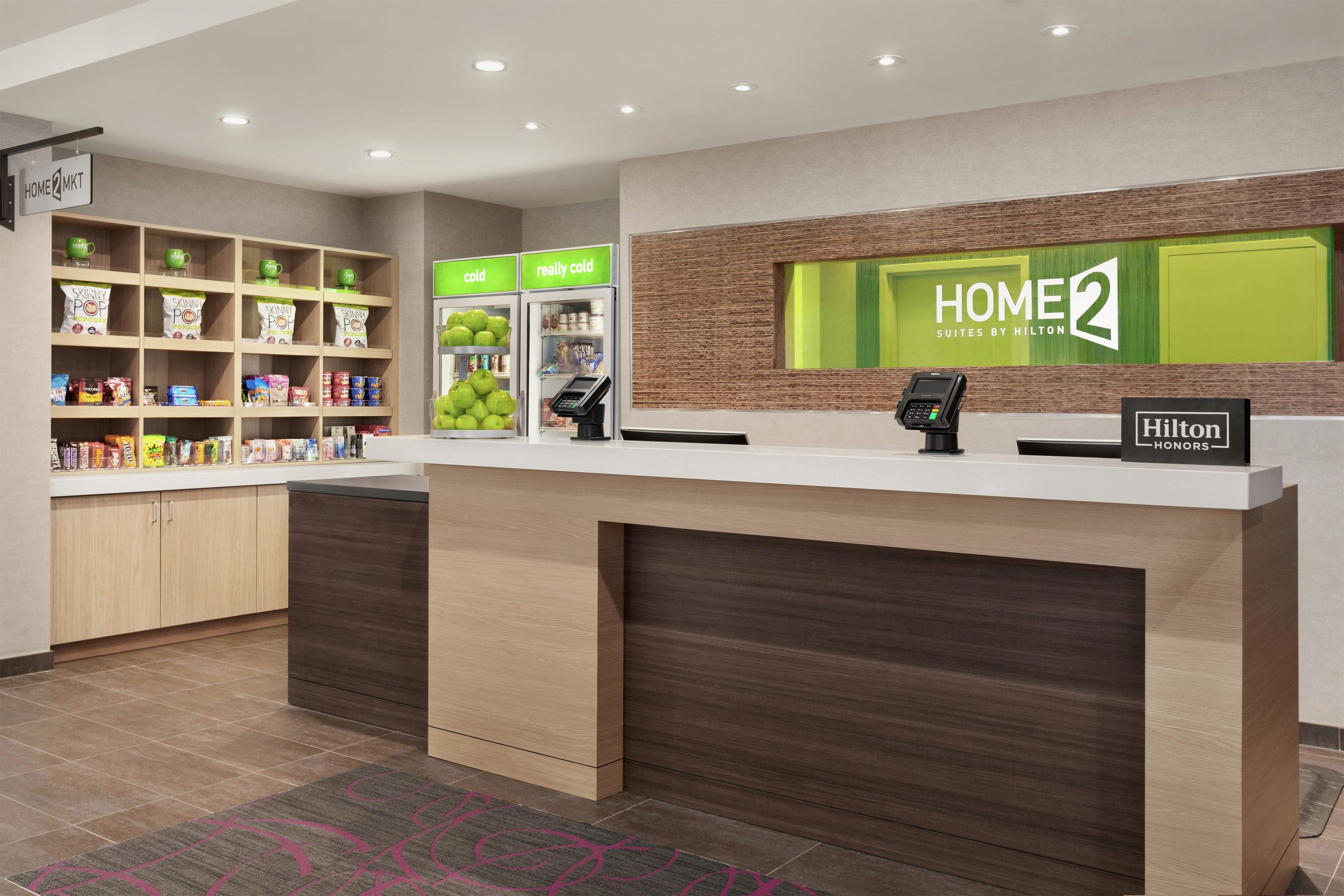 Ein Hotel-Empfangsbereich mit Theke, einem digitalen Kiosk und einer Selbstbedienungs-Snackstation.