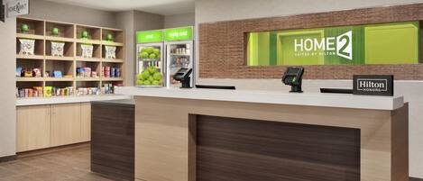 A hotel reception area with a counter, a digital kiosk, and a self-service snack station.