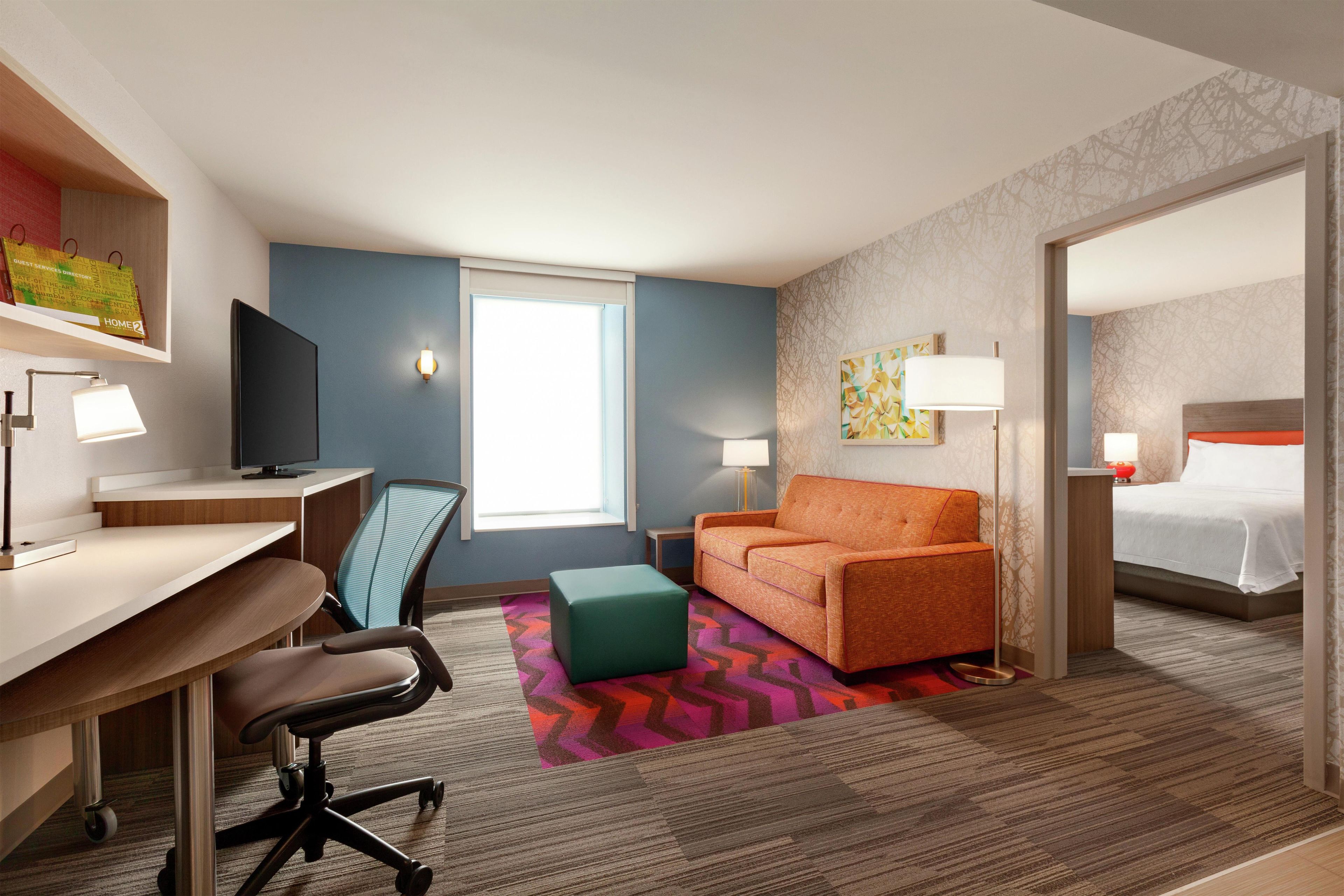 A hotel room with a desk, chair, sofa, and a bed.