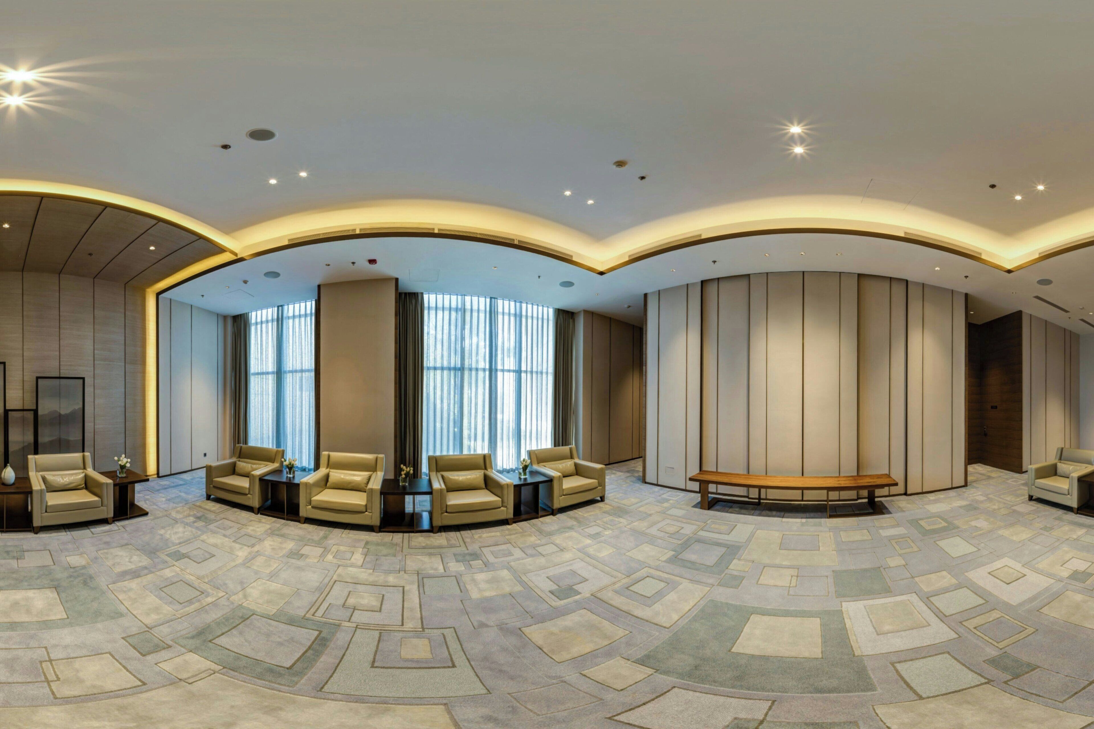 A spacious lobby with a patterned carpet, several sofas, and a wooden bench.