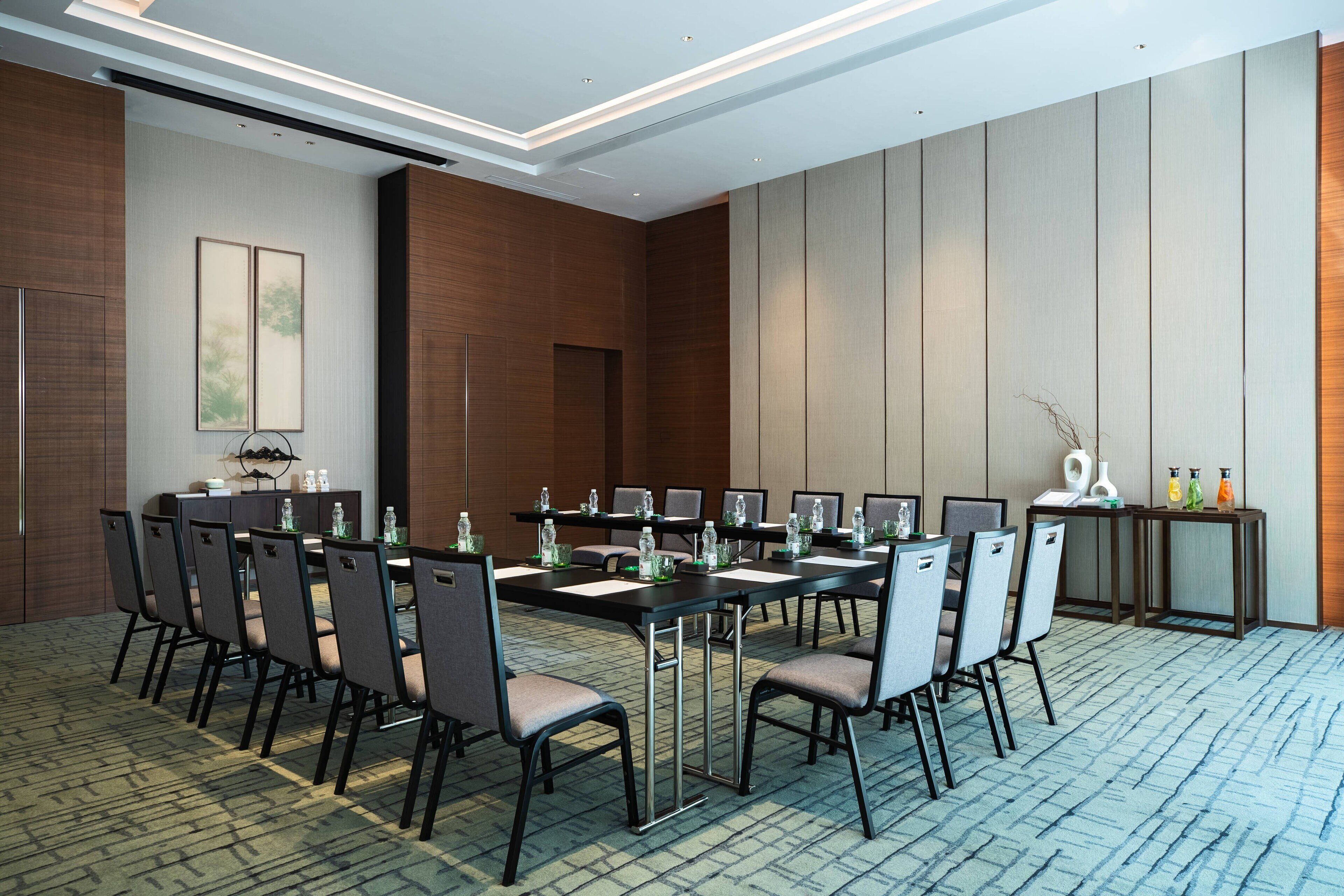 Un salón de conferencias con una larga mesa, sillas y botellas de agua.