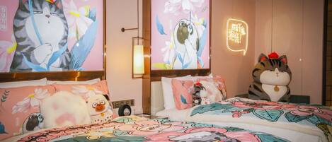 Quarto de hotel com duas camas, cada uma com roupa de cama estampada com flores e um grande mural na parede de um gato.
