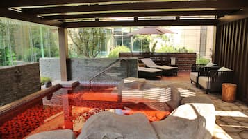 Zona de spa con hidromasaje, asientos y vistas al exterior.