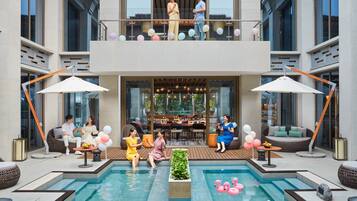 Un hotel moderno con zona de piscina, asientos al aire libre y un balcón decorado con globos.
