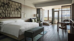 A modern hotel room with a large bed, a bench, a desk, and a view of the city. - Beijing Marriott Hotel Changping (Changping)