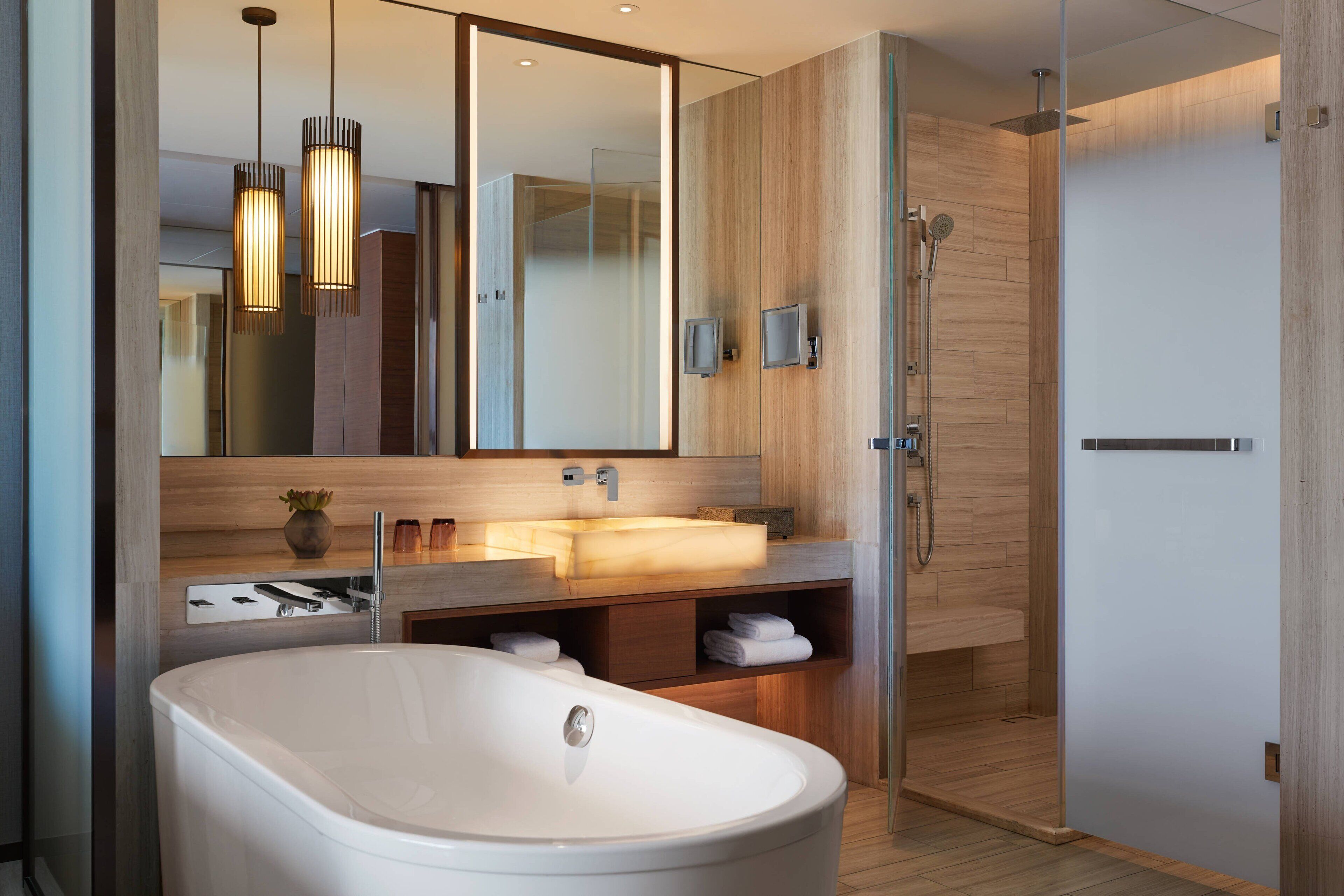 A modern bathroom with a freestanding bathtub, a large mirror, and a glass-enclosed shower area.