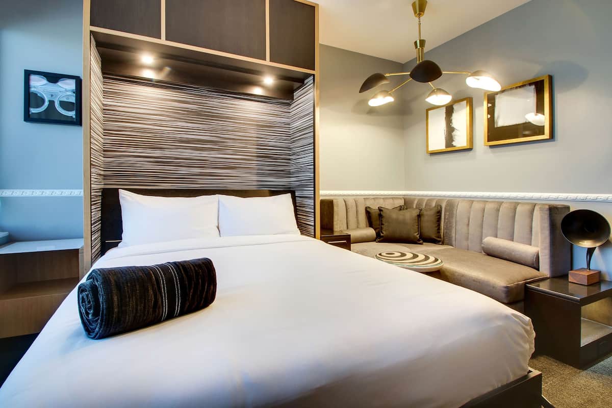 A modern hotel room with a large bed, a sofa, and a small table.