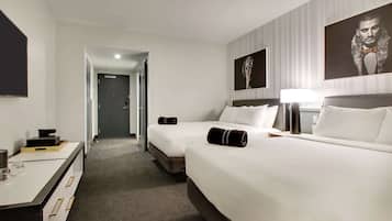 A hotel room with two beds, a desk, a lamp, and a large framed picture on the wall.