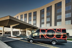A modern building with a black van parked in front.