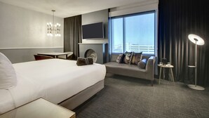 Hotelkamer met een groot bed, een slaapbank, een aan de muur bevestigde televisie, een klein tafeltje en een vloerlamp.