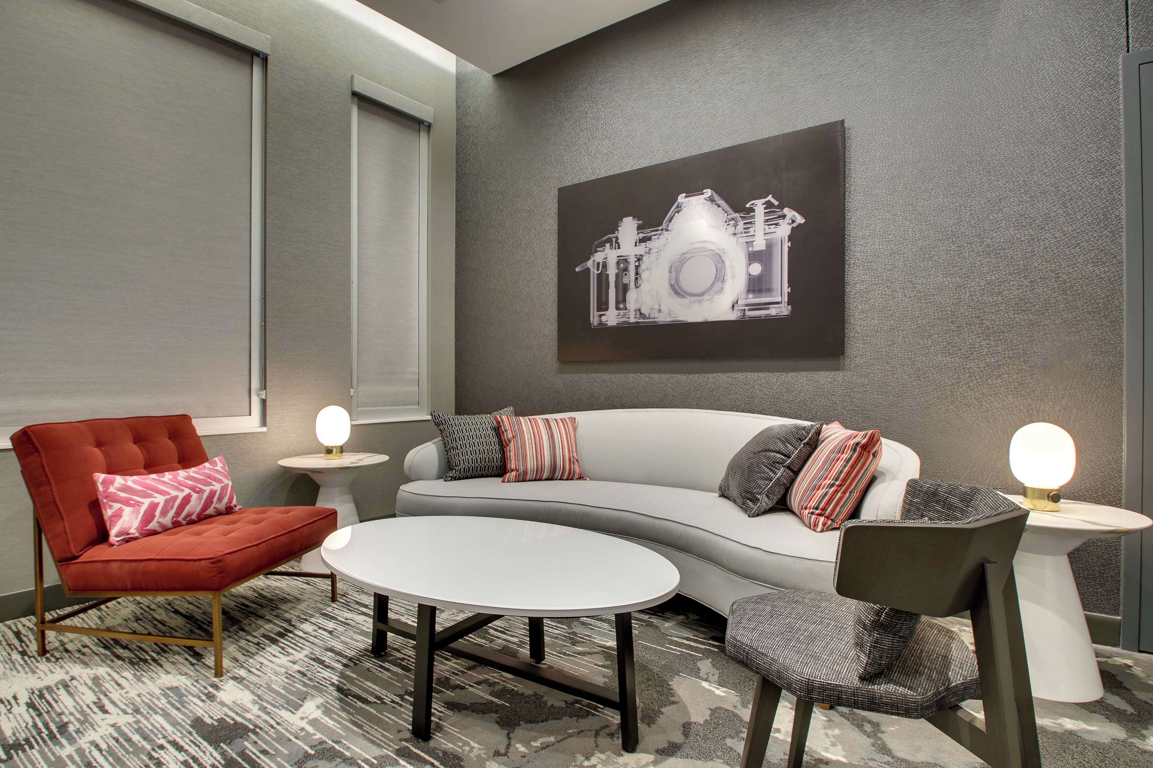 Un salon moderne comprenant un canapé, des fauteuils, une table basse et une œuvre d’art accrochée au mur.