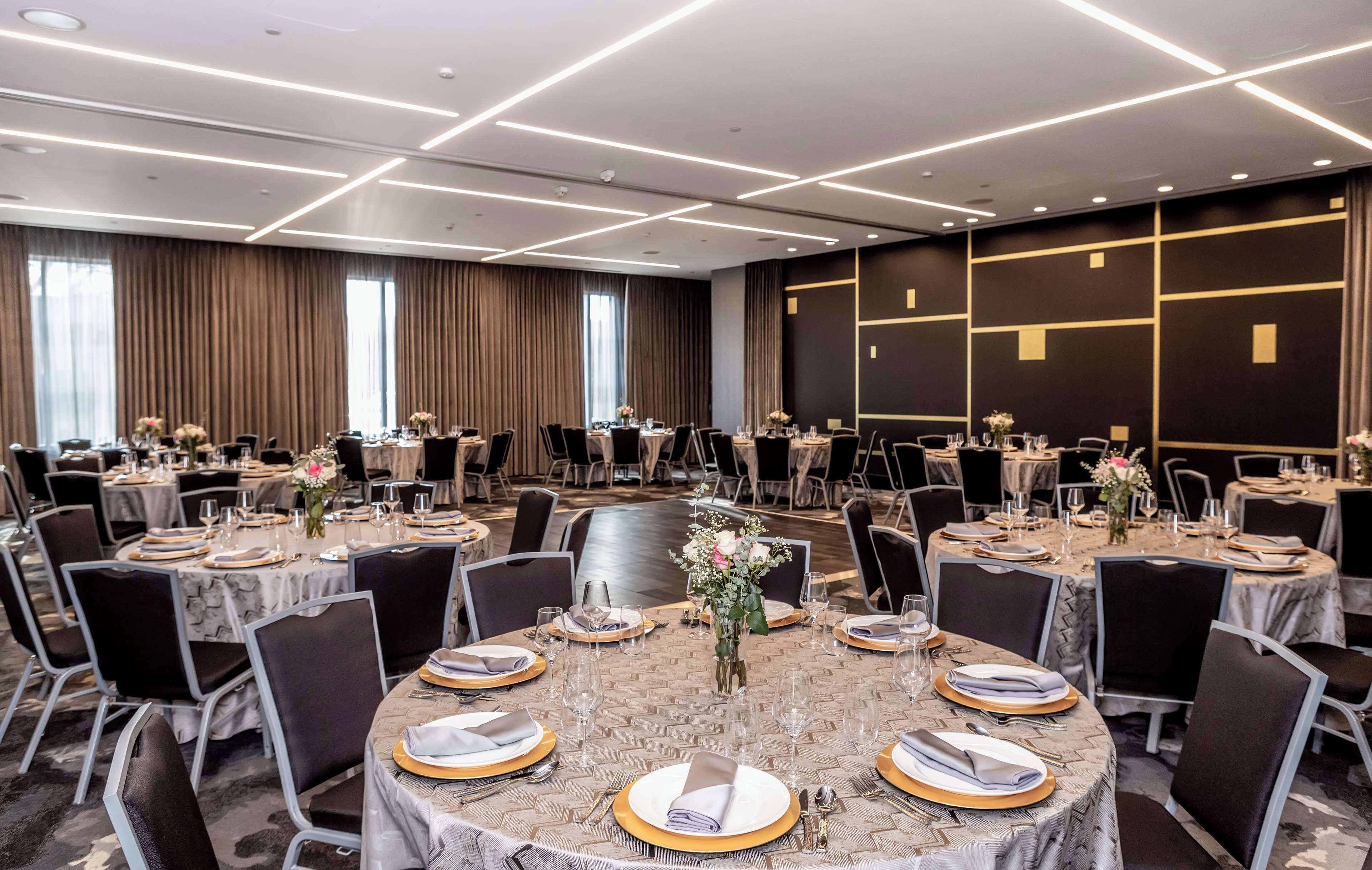 A conference room with round tables, black chairs, and gold accents.