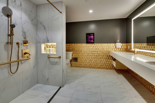 A modern bathroom with a marble shower, a golden-tiled wall, and a large mirror.