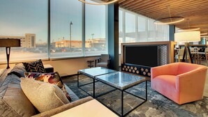 Een moderne woonkamer met een bank, een glazen salontafel en een roze fauteuil.
