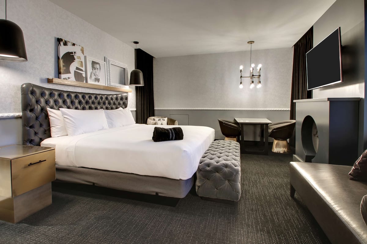 A modern hotel room with a large bed, a desk, a sofa, and a television.