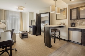 Una habitación de hotel moderna con comedor, kitchenette y una cama grande.