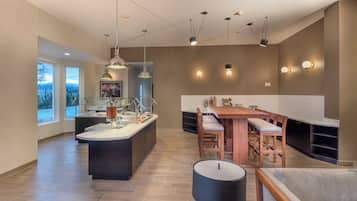 Una cocina moderna con una isla central, iluminación colgante y un comedor con mesa y sillas de madera.