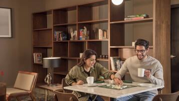 A room with a marble table, chairs, a bookshelf, and a Scrabble game.