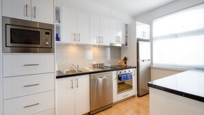 A modern kitchen with white cabinets, stainless steel appliances, and a wooden floor. - Hobart Cityscape (Hobart)