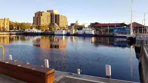 A waterfront marina with boats docked, a large building in the background, and a clear sky. - Hobart Cityscape (Hobart)