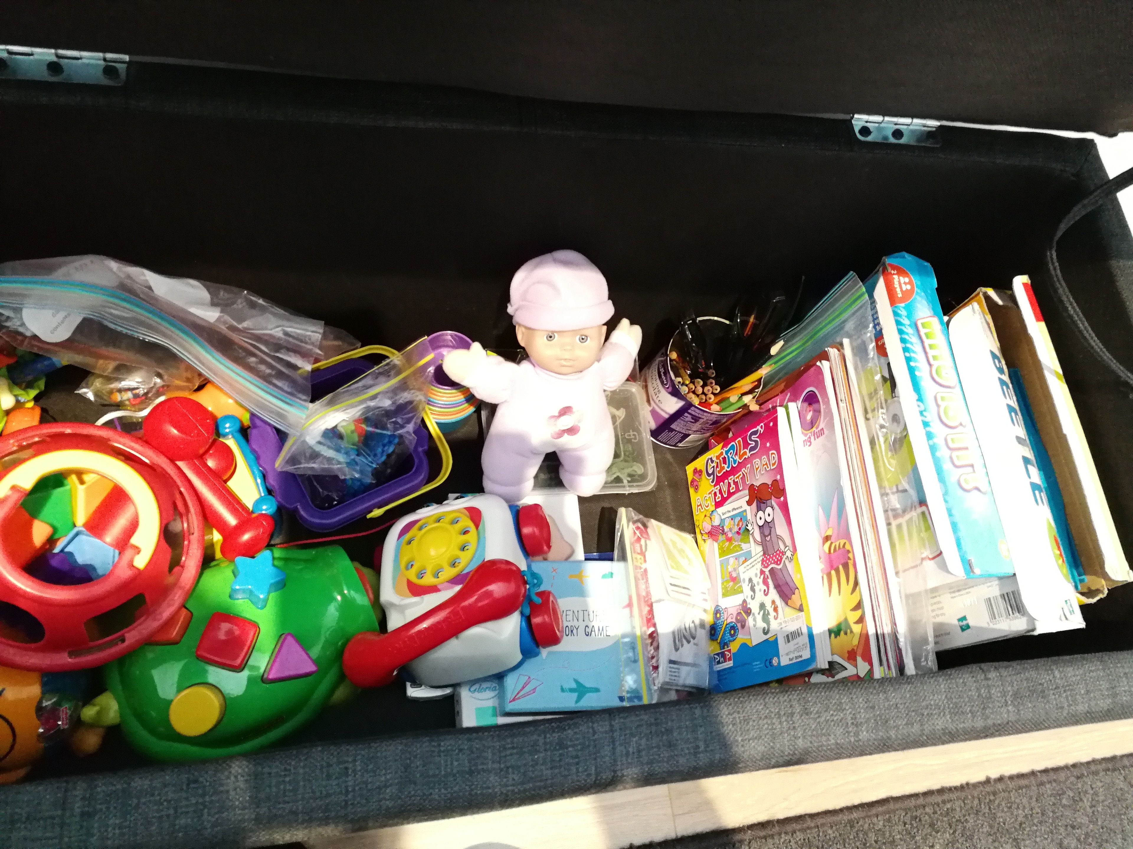 A suitcase filled with toys, books, and a doll.