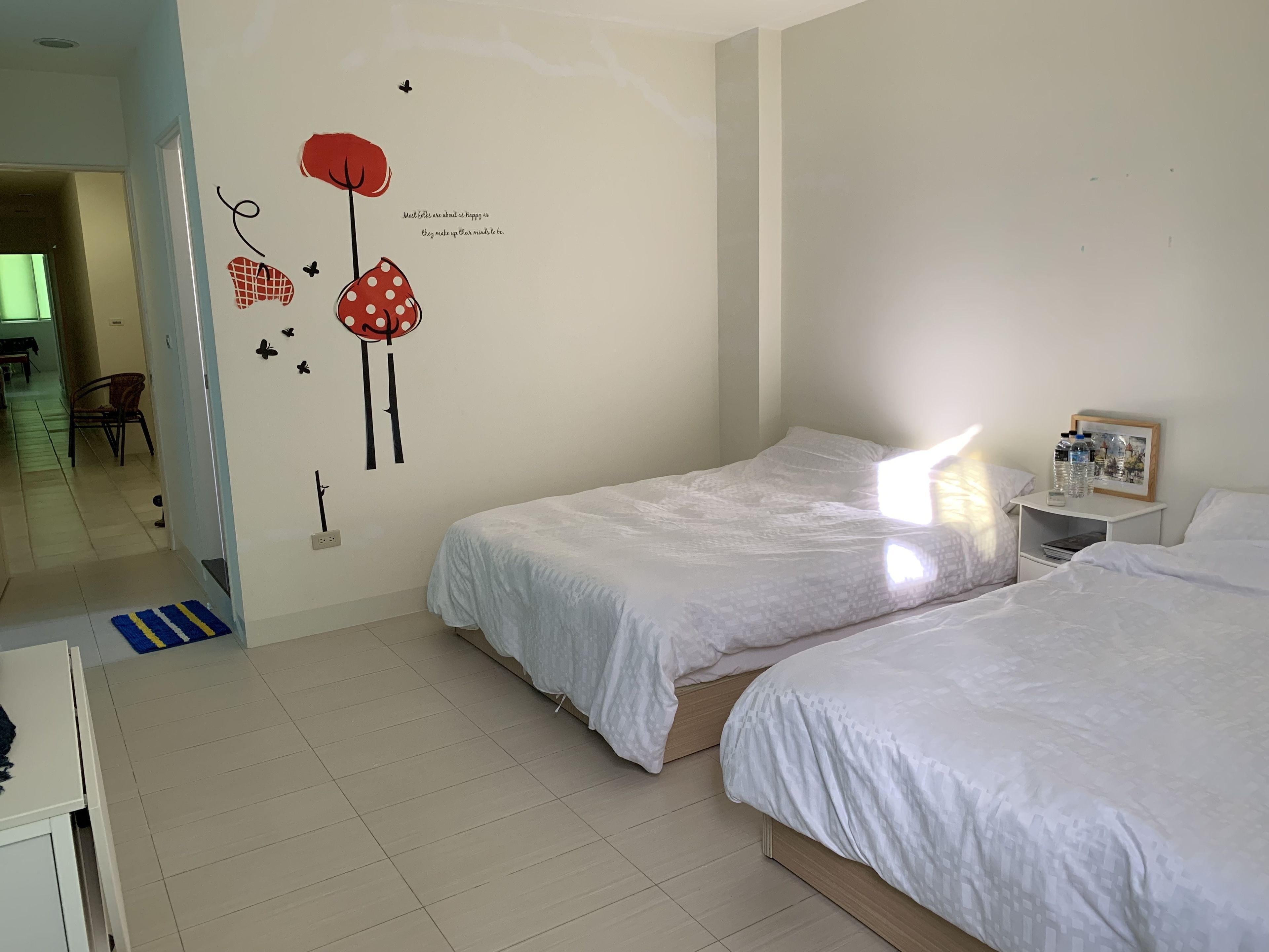 A hotel room with two beds, a nightstand with a mirror and a picture frame, and a wall with decorative stickers.