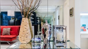 A reception area with a glass counter, a red sofa, and decorative vases. - Alcoves Greenbelt Park Place Makati (Makati)