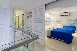 Et moderne hotelværelse med en glasbalkon, en seng med blåt sengetøj og et stort spejl der reflekterer værelset.