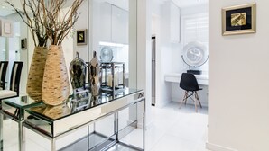A modern interior with a glass-top dining table, a black office chair, and a white wall with a framed picture. - Alcoves Greenbelt Park Place Makati (Makati)